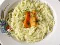 Domowy makaron, przepis babci, podany z marchewką i natką pietruszki na talerzu ozdobionym kłosami zbóż i kwiatami.