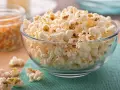 Misternie ułożony popcorn w szklanej misce. Czy popcorn jest zdrowy? To zależy od sposobu przygotowania, ale sam w sobie jest dobrym źródłem błonnika.
