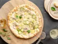 Pyszna pizza bianca z cukinią, cebulą i cytryną, ozdobiona bazylią i tymiankiem. Idealna na letni wieczór.