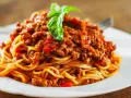 Pyszne spaghetti bolognese, idealne na prosty obiad. Aromatyczny sos mięsny z pomidorami i bazylią na złocistym makaronie.