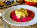 Pyszny barszcz czerwony zabielany, przepis babci. Na talerzu purée ziemniaczane z boczkiem i koperkiem w intensywnym, różowym barszczu.