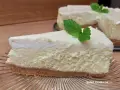Pyszny sernik z bitą śmietaną siostry Anastazji, udekorowany listkiem mięty, na szklanym talerzu.