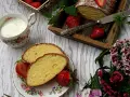 Pyszne ciasto z żółtek, udekorowane cukrem pudrem i truskawkami, podane z mlekiem.