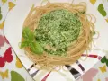 Makaron ze szpinakiem w sosie śmietanowo-serowym, udekorowany listkami bazylii. Pyszne danie na talerzu.