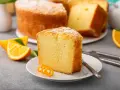 Wilgotna babka cytrynowa, posypana cukrem pudrem, z plasterkami pomarańczy i ozdobną skórką. Idealna na deser.