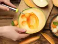 Ręka wydrąża kulki z melona, pokazując jego soczysty miąższ. Idealna przekąska, która ma mało kcal.