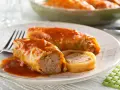 Dwa gołąbki w sosie pomidorowym, jeden przekrojony, ukazujący farsz. Obok kawałek gołąbka.