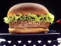 Soczysty hamburger z sałatą na czarnym talerzu.