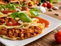 Pyszna tortilla z mięsem mielonym, polana sosem pomidorowym, ozdobiona bazylią i serem pleśniowym.