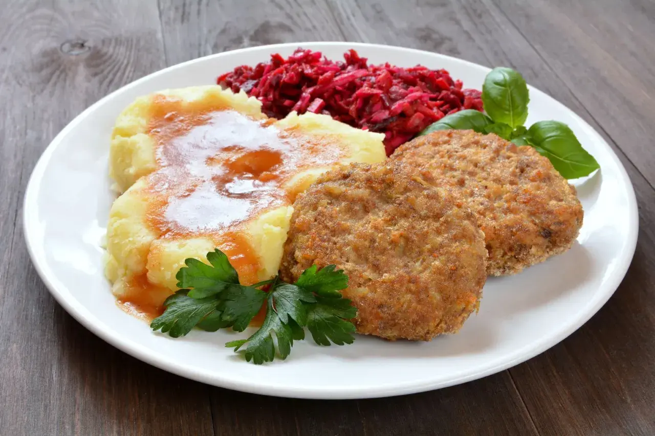Pyszne mielone z piekarnika, podane z purée ziemniaczanym, buraczkami i natką pietruszki.