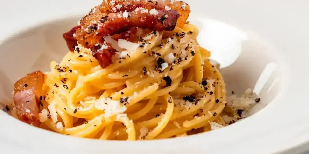 Spaghetti carbonara – przepis oryginalny ze śmietaną. Pyszne danie z makaronem, boczkiem i parmezanem, posypane świeżo mielonym pieprzem.