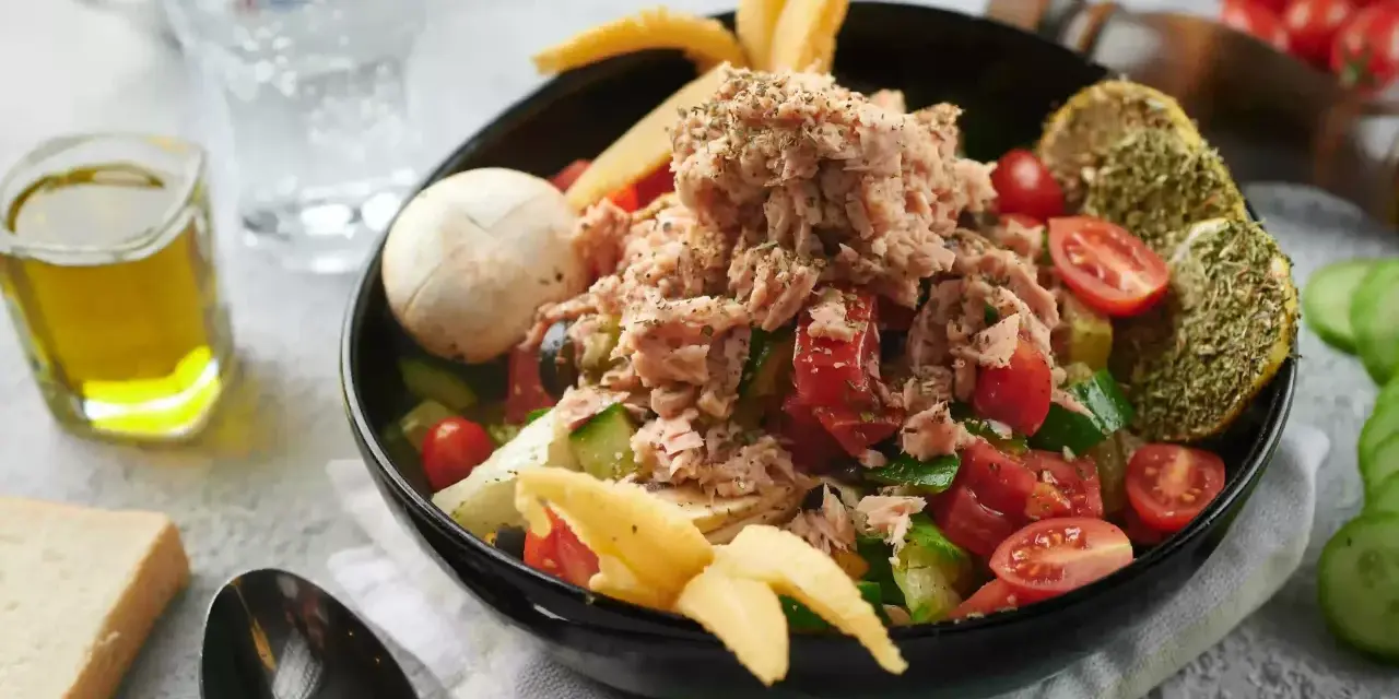 Sałatka z tuńczykiem, pomidorami i ogórkiem, inspirowana dieta śródziemnomorska przepisy. Z oliwą i pieczywem.