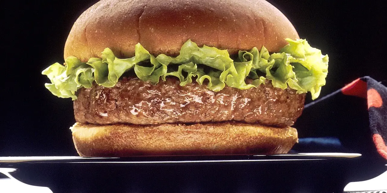 Soczysty hamburger z sałatą na czarnym talerzu.