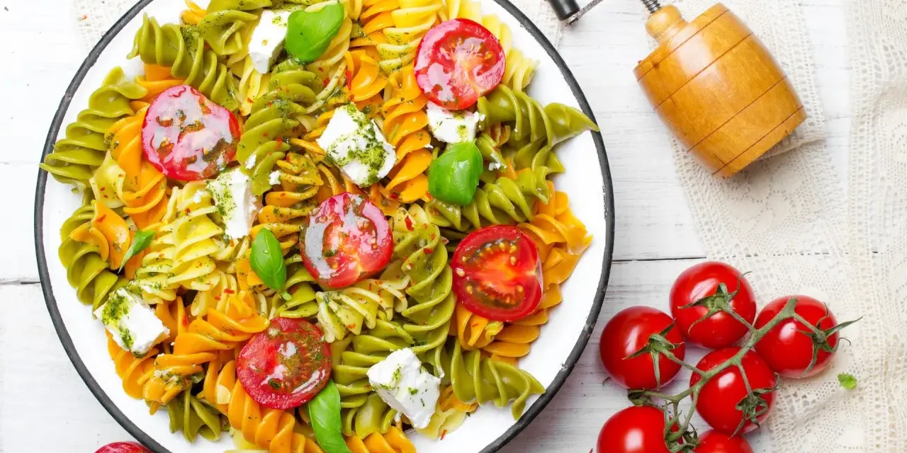 Kolorowy makaron z zielonego groszku, pomidorkami koktajlowymi i fetą, polany pesto.