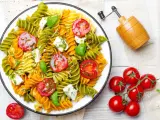 Kolorowy makaron z zielonego groszku, pomidorkami koktajlowymi i fetą, polany pesto.