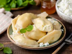 Pyszne pierogi z serem, jak u babci. Delikatne ciasto i kremowe nadzienie, posypane świeżym twarogiem i miętą.