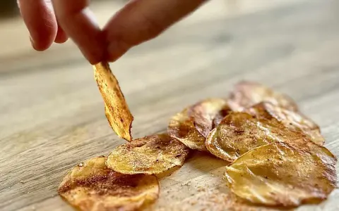 Chrupiące chipsy z piekarnika, doprawione ziołami, unoszą się na drewnianym blacie. Palce sięgają po kolejną przekąskę.