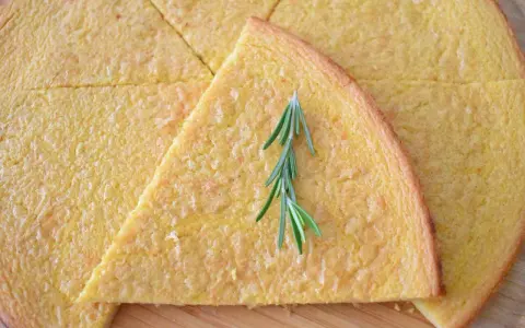 Schiacciata pokrojona w trójkąty, ozdobiona gałązką rozmarynu.