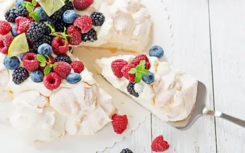 Beza pavlova która zawsze wychodzi, udekorowana świeżymi malinami, borówkami, jeżynami i plasterkami limonki.
