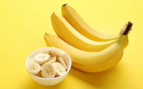 Kilka żółtych bananów i miseczka pokrojonych plasterków. Poznaj banan wartości odżywcze i ciesz się zdrową przekąską!