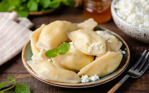 Pyszne pierogi z serem, jak u babci. Delikatne ciasto i kremowe nadzienie, posypane świeżym twarogiem i miętą.