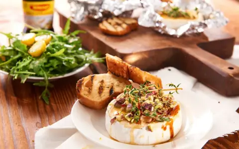 Pyszny camembert z grilla, polany miodem i posypany pistacjami, podany z grzankami i sałatką. Idealny na letnie wieczory.