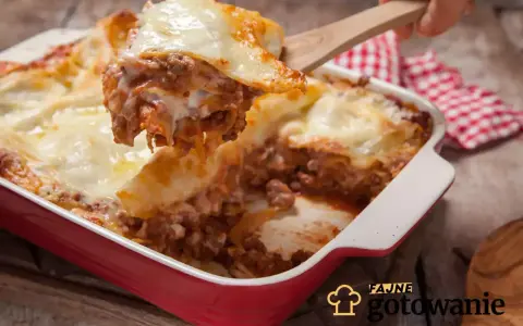 Pyszna, gorąca lasagne z mięsem mielonym i ciągnącym serem, właśnie nakładana drewnianą łopatką. Idealna na rodzinny obiad.