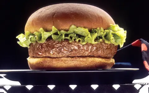 Soczysty hamburger z sałatą na czarnym talerzu.