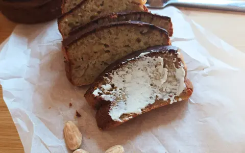 Pyszny chlebek bananowy z airfryera, pokrojony w kromki, jedna posmarowana masłem. Idealny na śniadanie.