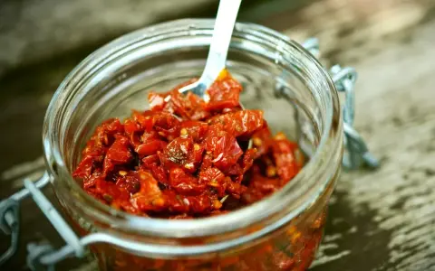 Słoik pełen aromatycznej pasty z suszonych pomidorów, gotowej do użycia.