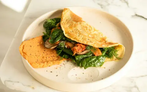 Omlet z air fryera z farszem ze szpinaku, pieczarek i kimchi. Obok porcja pomarańczowego hummusu.