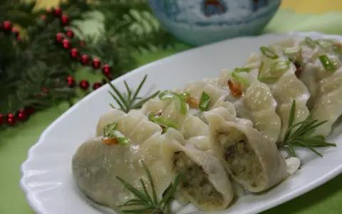 Pyszne pierogi ukraińskie, udekorowane szczypiorkiem i rozmarynem, na świątecznym stole.