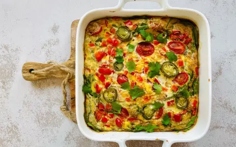 Pyszny omlet z piekarnika z pomidorkami, papryką i jalapeño, udekorowany natką pietruszki.