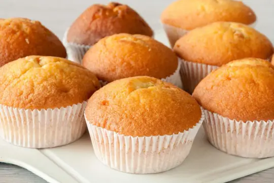 Złociste muffinki w papierowych foremkach, gotowe do podania. Idealne na uniwersalny przepis na muffinki, który sprawdzi się zawsze.
