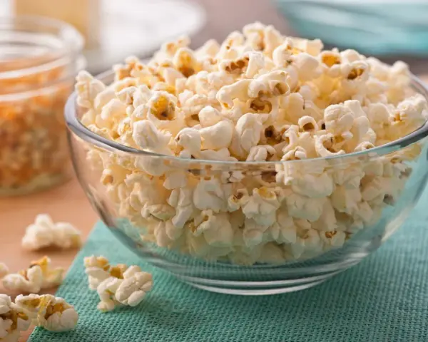 Misternie ułożony popcorn w szklanej misce. Czy popcorn jest zdrowy? To zależy od sposobu przygotowania, ale sam w sobie jest dobrym źródłem błonnika.