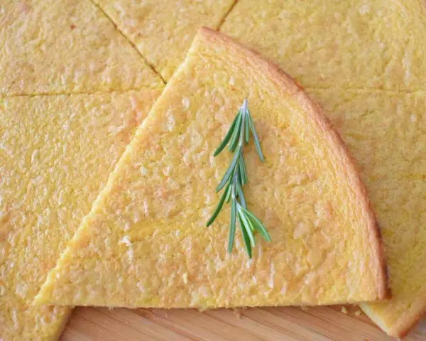 Schiacciata pokrojona w trójkąty, ozdobiona gałązką rozmarynu.