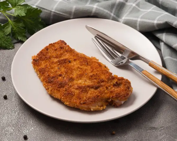 Złocisty kotlet schabowy na talerzu, gotowy do spożycia. Zastanawiasz się nad kotlet schabowy kcal?