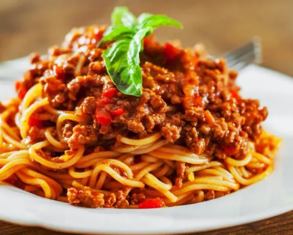 Pyszne spaghetti bolognese, idealne na prosty obiad. Aromatyczny sos mięsny z pomidorami i bazylią na złocistym makaronie.