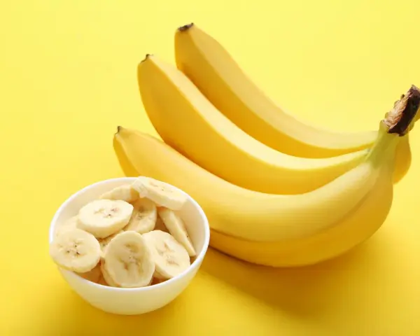Kilka żółtych bananów i miseczka pokrojonych plasterków. Poznaj banan wartości odżywcze i ciesz się zdrową przekąską!