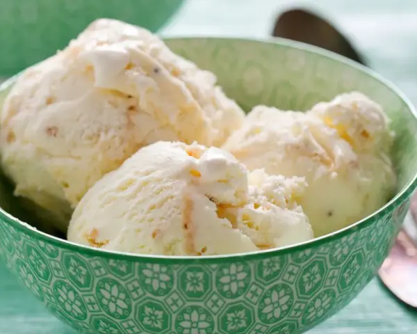 Puszyste lody z mascarpone, pełne delikatnych kawałków, kuszą kremową konsystencją w zielonej miseczce.