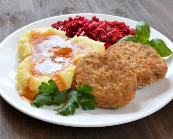 Pyszne mielone z piekarnika, podane z purée ziemniaczanym, buraczkami i natką pietruszki.