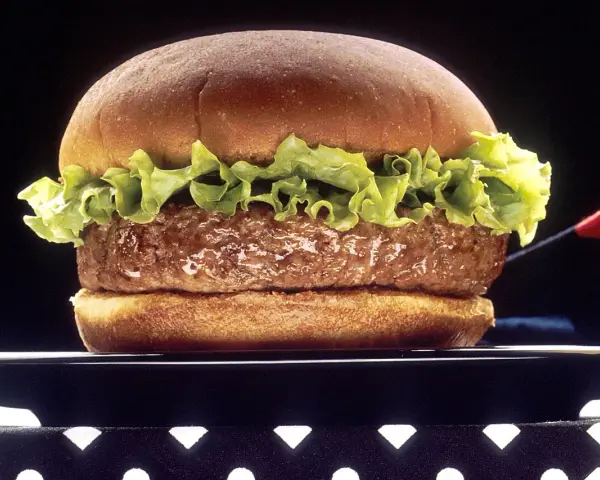 Soczysty hamburger z sałatą na czarnym talerzu.