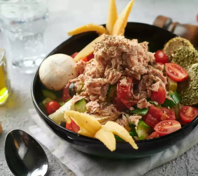 Sałatka z tuńczykiem, pomidorami i ogórkiem, inspirowana dieta śródziemnomorska przepisy. Z oliwą i pieczywem.