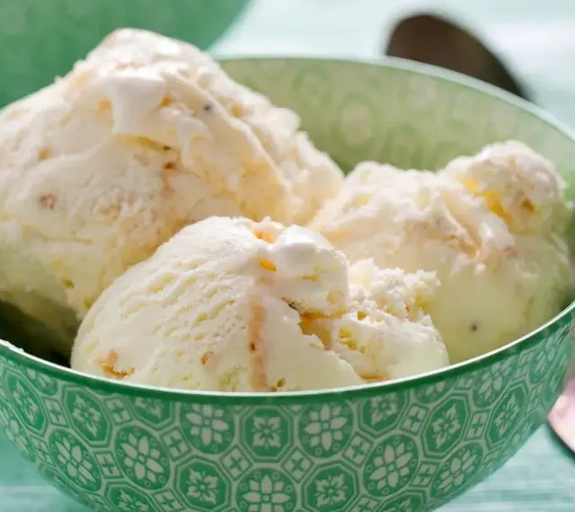 Puszyste lody z mascarpone, pełne delikatnych kawałków, kuszą kremową konsystencją w zielonej miseczce.