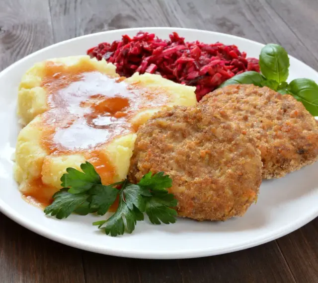 Pyszne mielone z piekarnika, podane z purée ziemniaczanym, buraczkami i natką pietruszki.