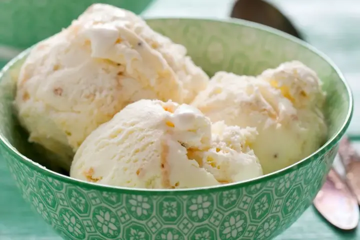 Puszyste lody z mascarpone, pełne delikatnych kawałków, kuszą kremową konsystencją w zielonej miseczce.