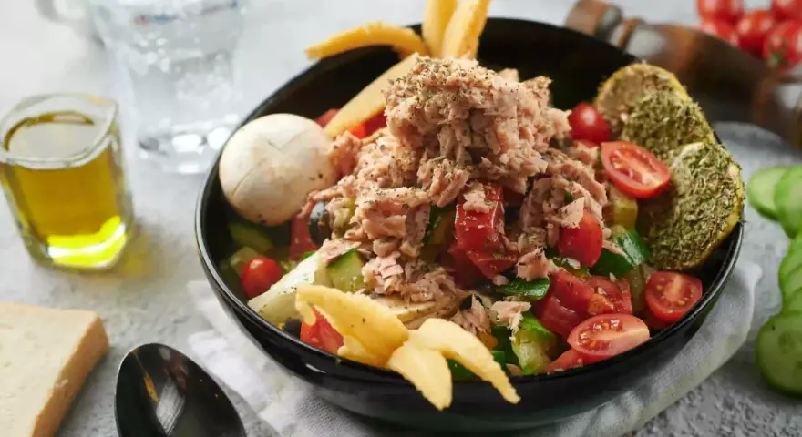 Sałatka z tuńczykiem, pomidorami i ogórkiem, inspirowana dieta śródziemnomorska przepisy. Z oliwą i pieczywem.