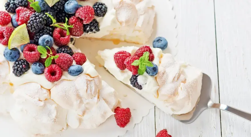 Beza pavlova która zawsze wychodzi, udekorowana świeżymi malinami, borówkami, jeżynami i plasterkami limonki.