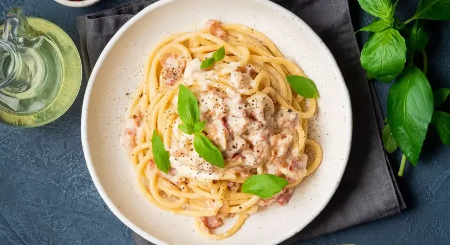 Pyszna carbonara na talerzu, idealna inspiracja, jak zrobić carbonare. Podana z bazylią i pieprzem.