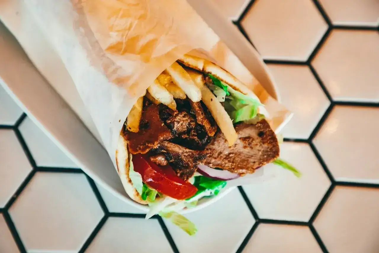 Pyszny kebab z mięsem, frytkami, warzywami i sosem. Idealny na szybki posiłek, choć warto pamiętać o jego kaloryczności.